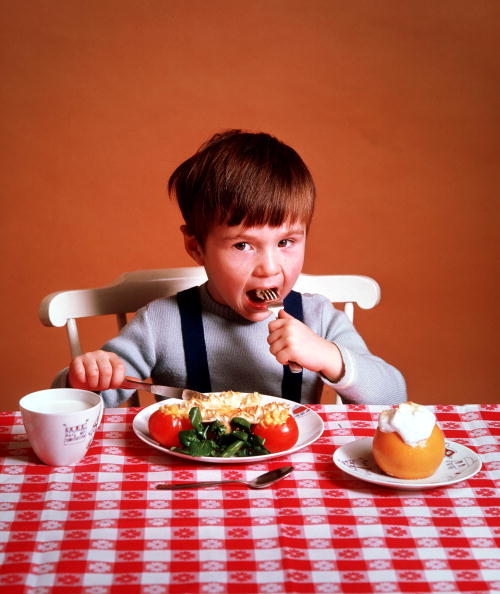 Classic Collection, Page 15, 10371613. A little boy sitting at a table, eating his dinner . With glass of milk and red gingham table cloth. (1964).